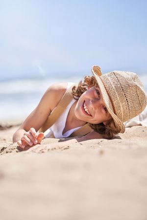 Smiling boy relaxing on sandy beach in summer
