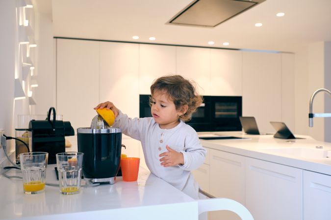 Boy squeezing orange using juicer in kitchen