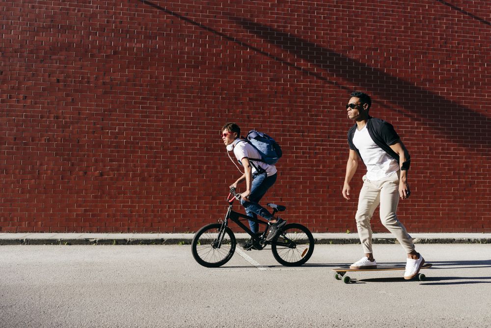 Young Black men riding bicycle and skateboard