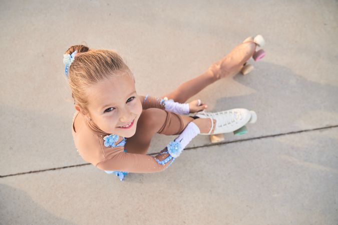 Cheerful girl tying shoelaces on roller skate before training