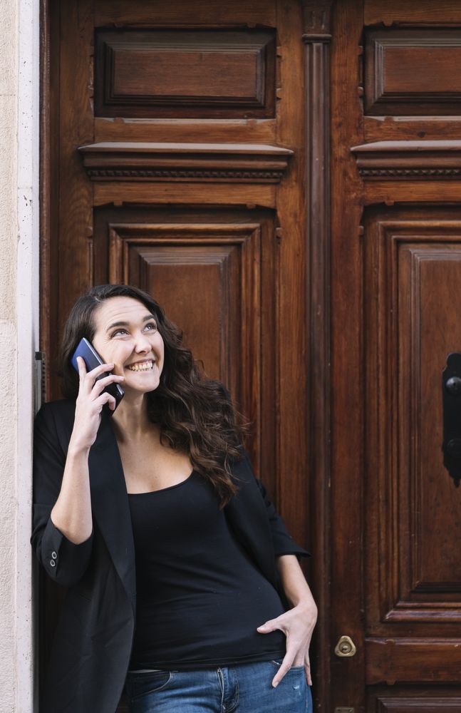 Young female using mobile phone on wooden door