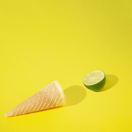 Ice cream cone with lime half on yellow background