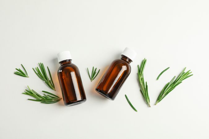 Flat lay composition with rosemary oil and leaves on plain background, space for text