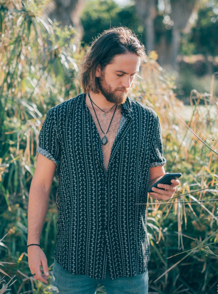 Young hipster man texting in jungle