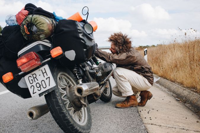 Man fixing motorcycle on side of road
