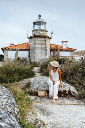 Woman in hat standing against beacon on seashore