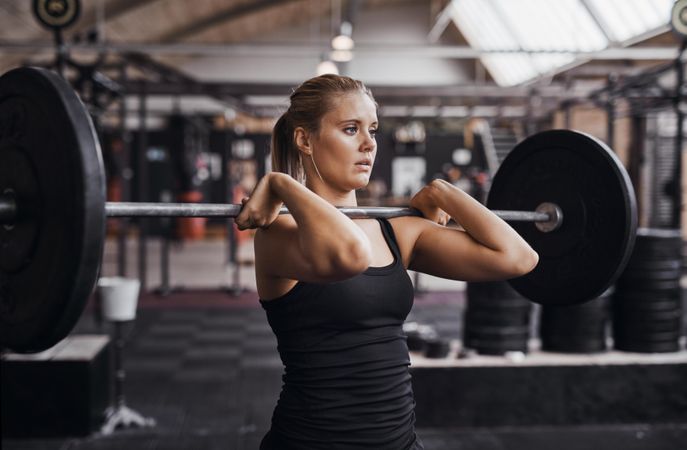 Blonde woman holding barbell at her shoulders