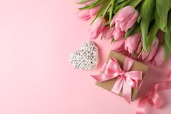 Pink tulips, gift box and decorative heart on pink background, space for text