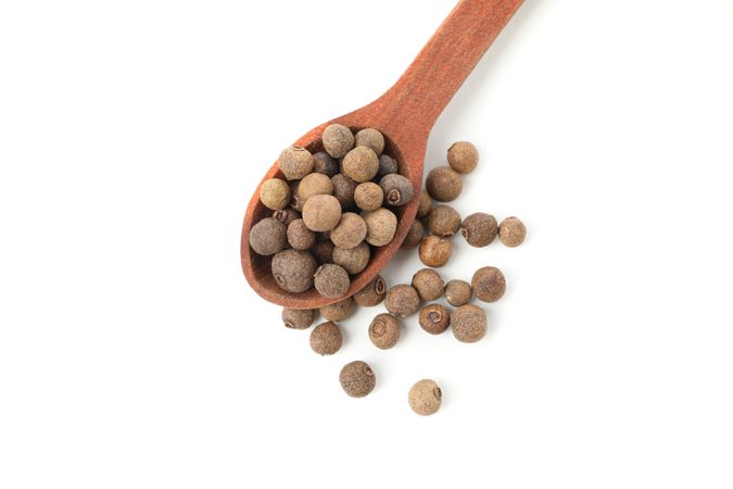 Close up top view of wooden spoon with peppercorns