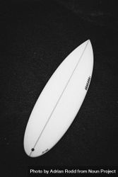 Surfboard lying on dark sand, vertical 5QZZN4