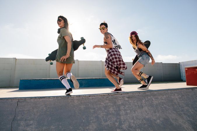 Three women walking at top of ramp at a skate park in the summer