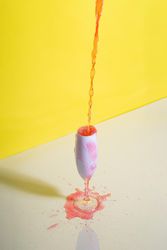 Rose champagne poured into glass against yellow background