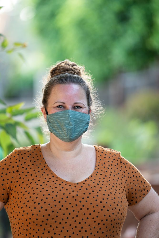 Portrait of beautiful woman in PPE mask with curly hair smiling at camera