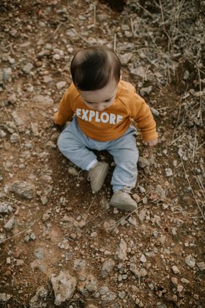 Top view of baby boy sitting on a path outside