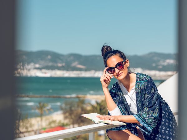 Relaxed woman with book sitting on balcony