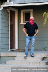 Full length shot of man in casual attire and mask standing on front porch of house 4MGj10