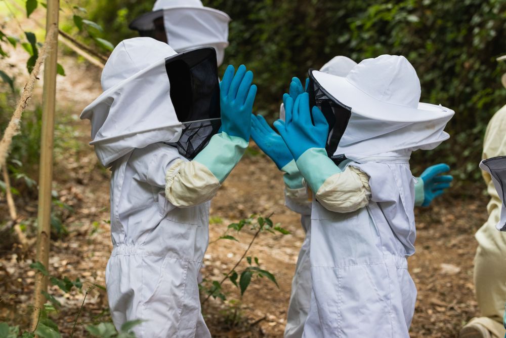 Faceless group of children in protective uniform in apiary