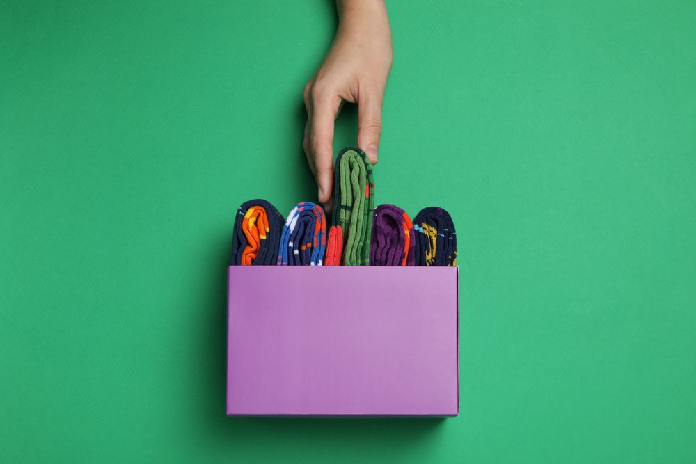 Bright socks with a print, in a box with a hand.