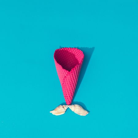Sea shells with pink waffle cone on bright blue background