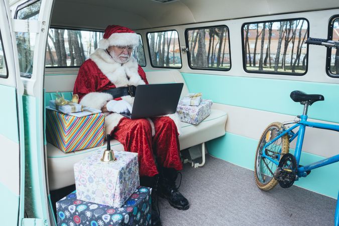 Santa Claus working at laptop in van