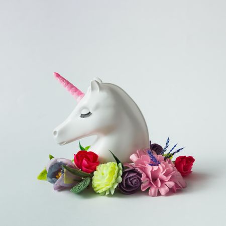 Painted unicorn head with colorful flowers and leaves on bright background