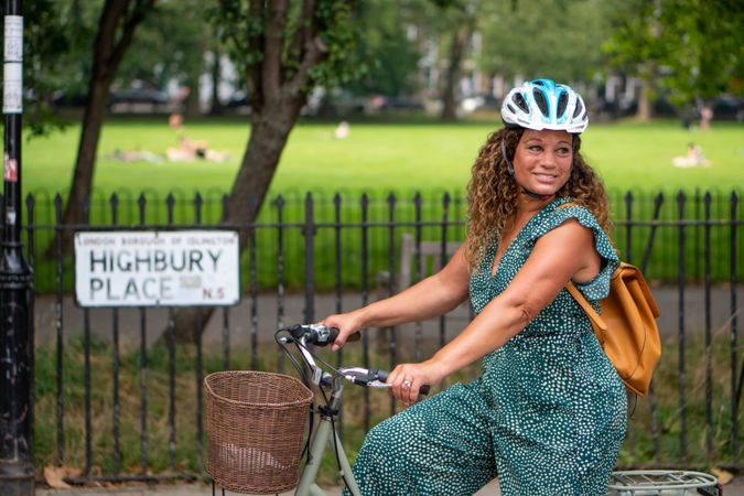 Smiling Black woman riding bike next to park