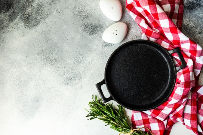Top view of cast iron pan with rosemary and kitchen towel
