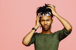Portrait of a young man holding his head, isolated on pink studio background