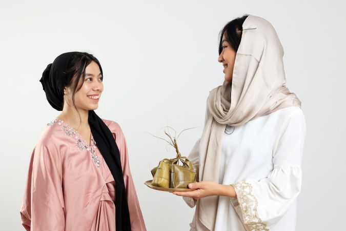 Two Female Sharing Ketupat, Indonesian Rice Cake Popular for Eid Al Fitr