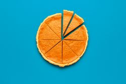 Homemade sliced pumpkin pie on a blue table