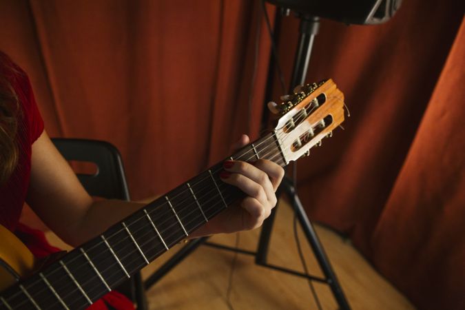 Crop woman playing guitar on stage