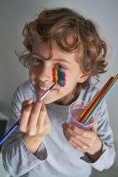 Happy child drawing rainbow on face