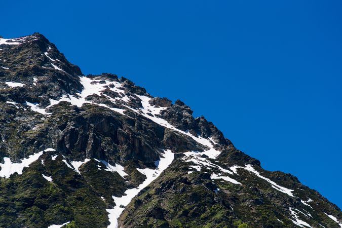 Snow-covered mountain peak with green forested slopes below.