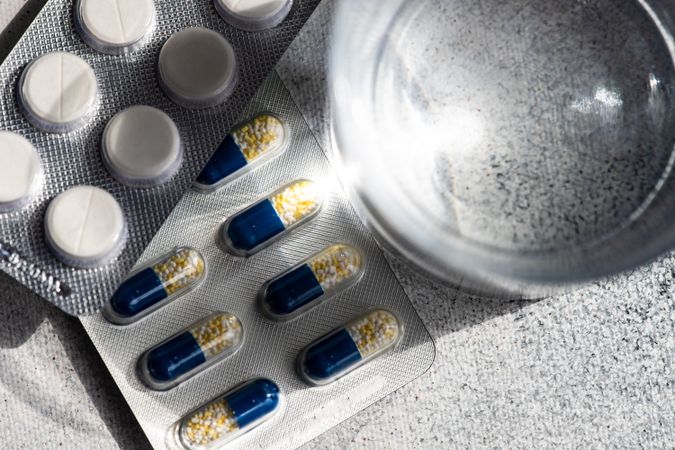 Top view of pills and glass of water on counter