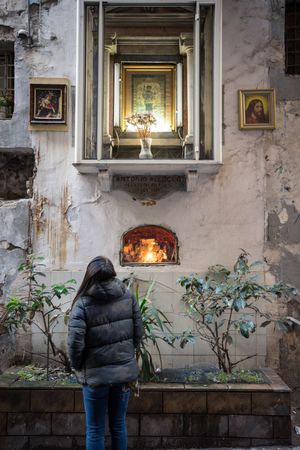Unrecognizable woman looking at window of shabby church