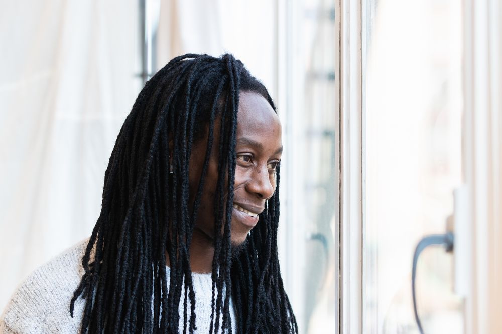 Black man looking at window on street