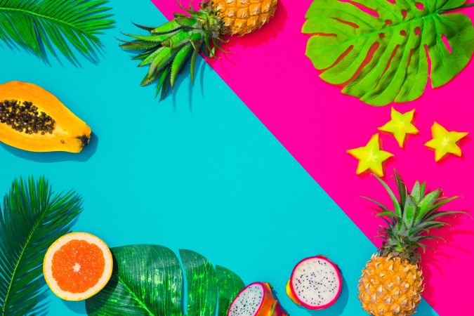 Tropical fruit, pineapple, papaya, dragonfruit on bright blue and pink background with palm leaves
