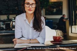 Woman in eyeglasses relaxing in cafe with notebook and coffee 0ydk1b