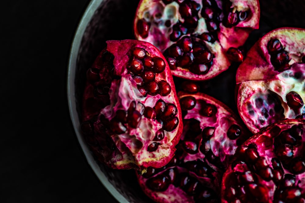 Open pomegranate in dark bowl