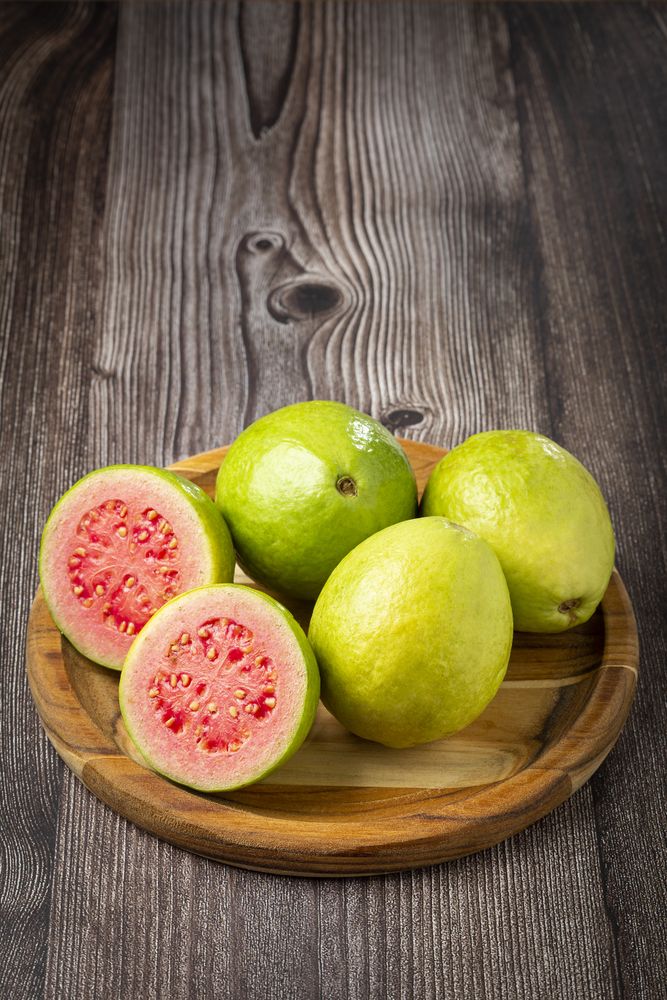 Fresh sliced guavas on wooden table.