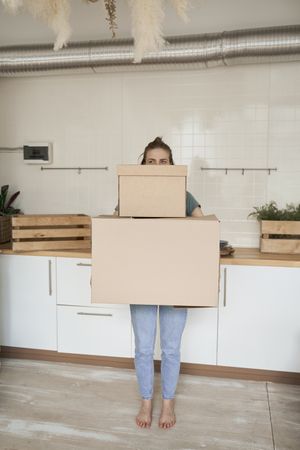 Young woman carrying big carton boxes in house