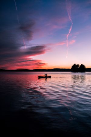 Silhouette of person on boat on body of water during sunset