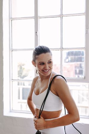 Young happy woman holding a jump rope after fitness class