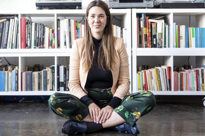 Portrait of a smiling woman sitting cross legged at home looking at camera