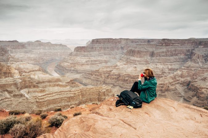 Female relaxing on cliff and admiring picturesque view