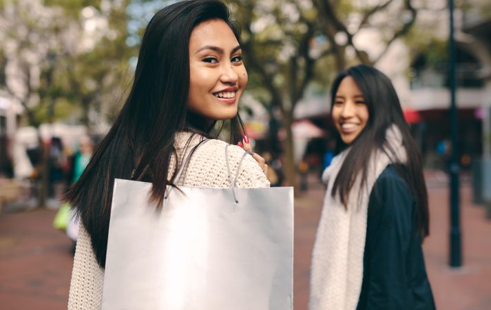Woman looking back over her shoulder with bag while shopping