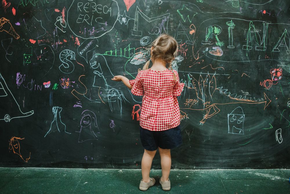 Girl drawing at school in writing green board