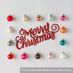 Border of colorful Christmas bauble decorations on light background with “Merry Christmas” bEyMMb