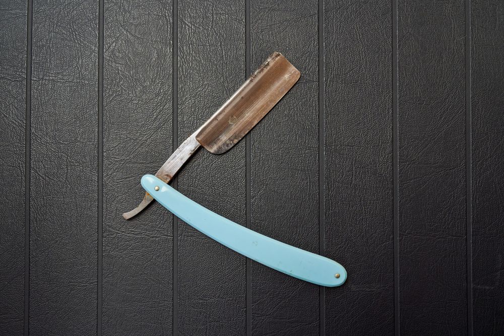 Rusty metal razor on black background