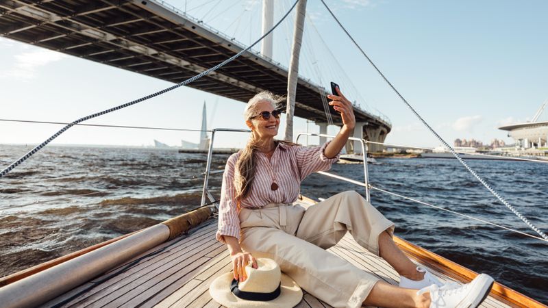Happy mature woman on yacht trip taking a selfie